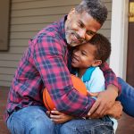 Father Hugging Son on Front Porch